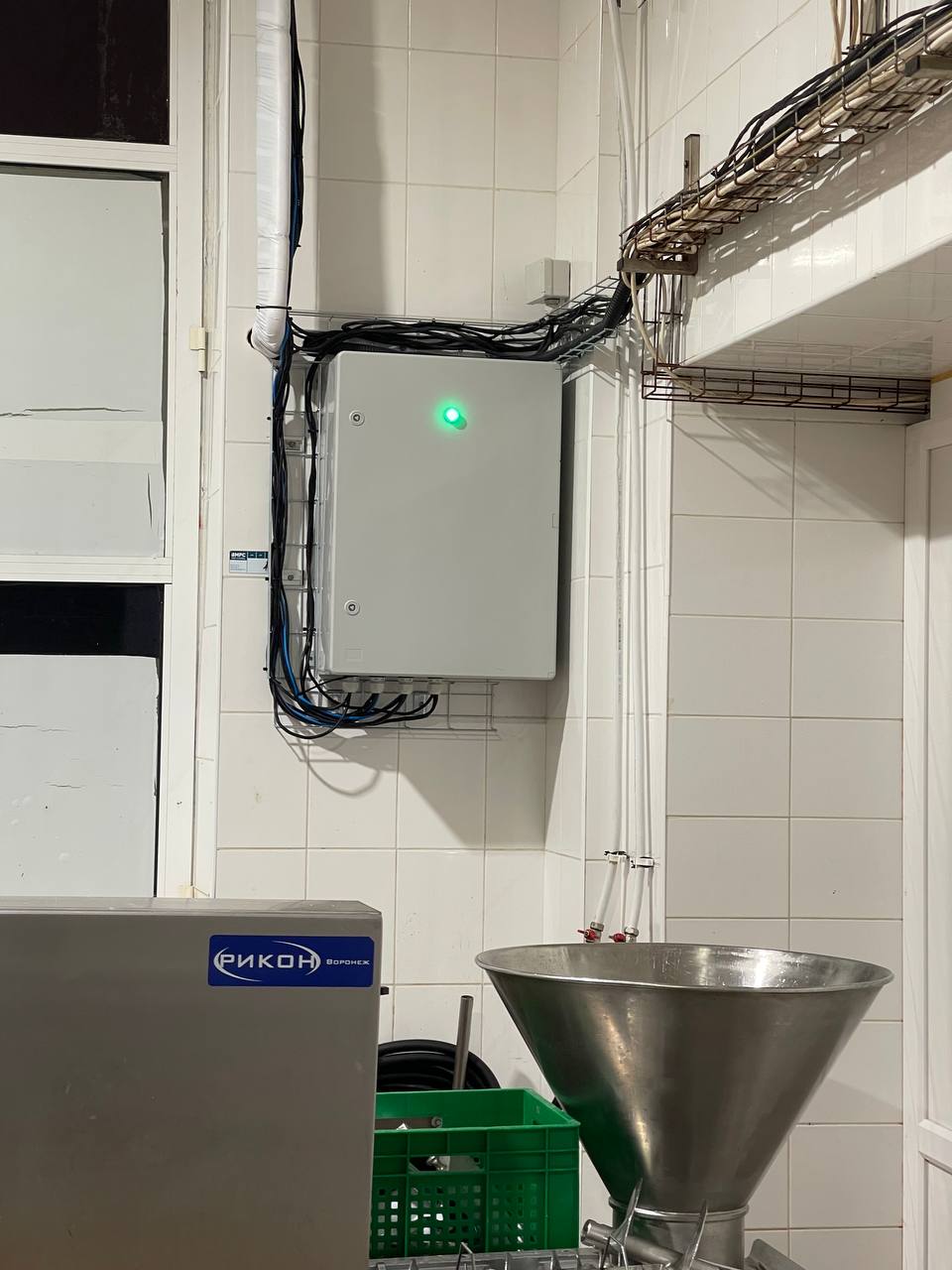 Panou electric de control instalat într-un spațiu de producție, cu cabluri tehnice, trasee metalice și echipamente industriale auxiliare.