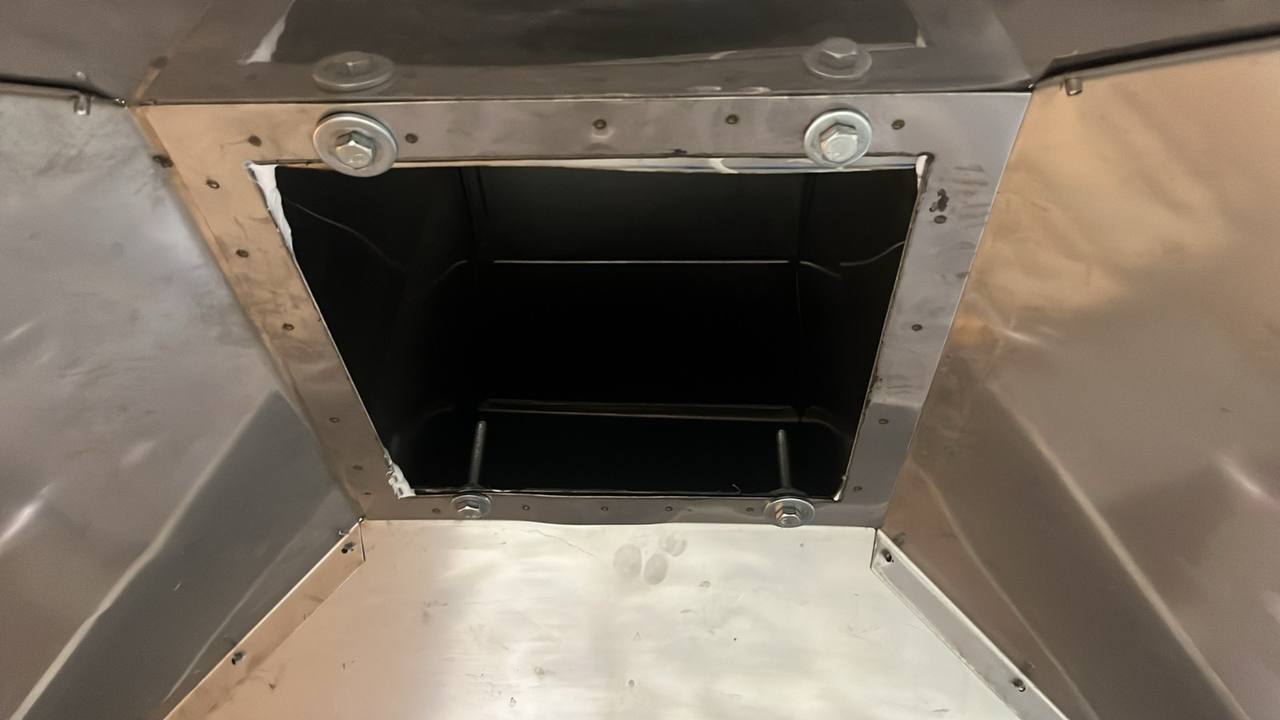 Detaliu al unei deschideri de extracție dintr-un sistem de ventilație industrială, cu ramă metalică, șuruburi de fixare și carcasă din inox.