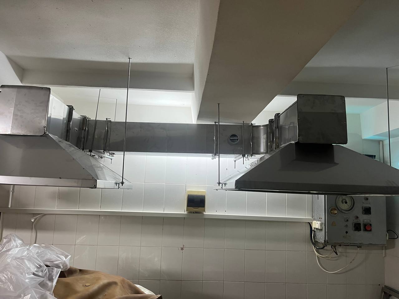 Sistem de ventilație industrială cu hote de extracție, conducte metalice și trasee suspendate instalate într-un spațiu de producție.